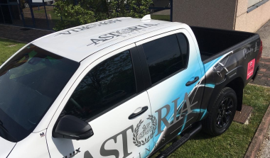 Vista laterale di pickup bianco decorato con pellicole stampate e scritte pubblicitarie