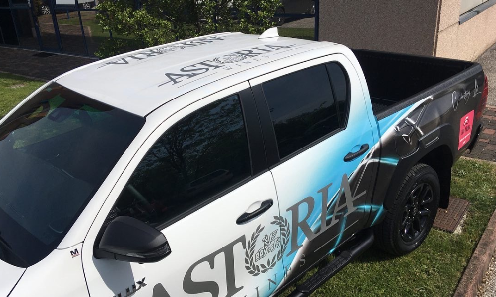 Vista laterale di pickup bianco decorato con pellicole stampate e scritte pubblicitarie