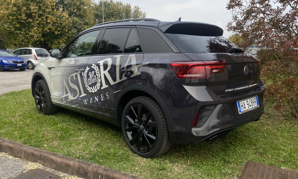 Vista posteriore laterale di SUV decorato con scritte pubblicitarie e logo